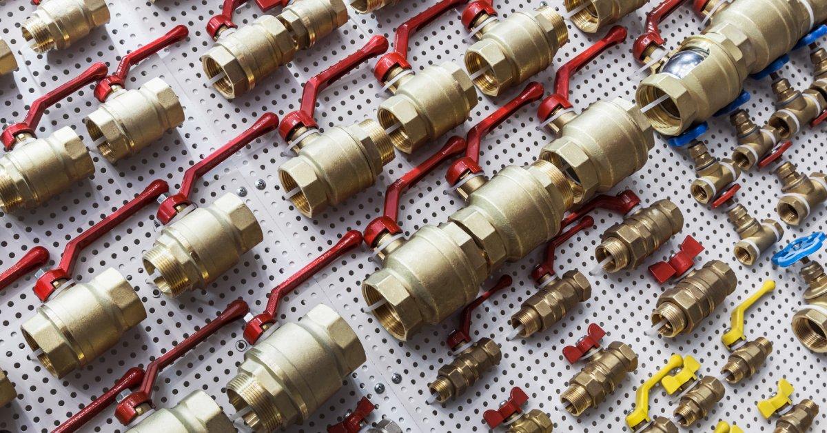 A close-up of numerous different water ball valves for plumbing or gas works. They're all gold and red.